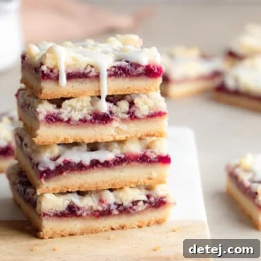 close up on a stack of 4 vegan raspberry bars on a cutting board.