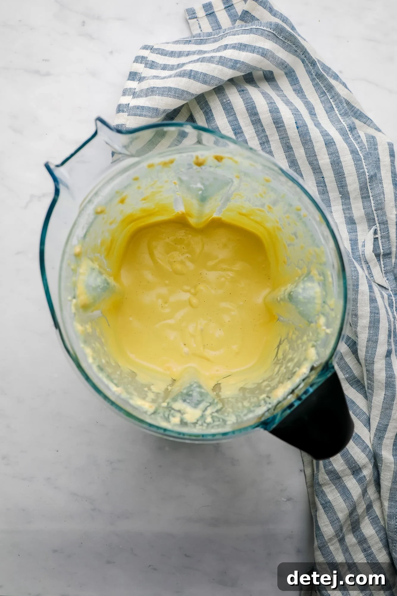 A creamy yellow cashew-based salad dressing being blended in a high-speed blender.