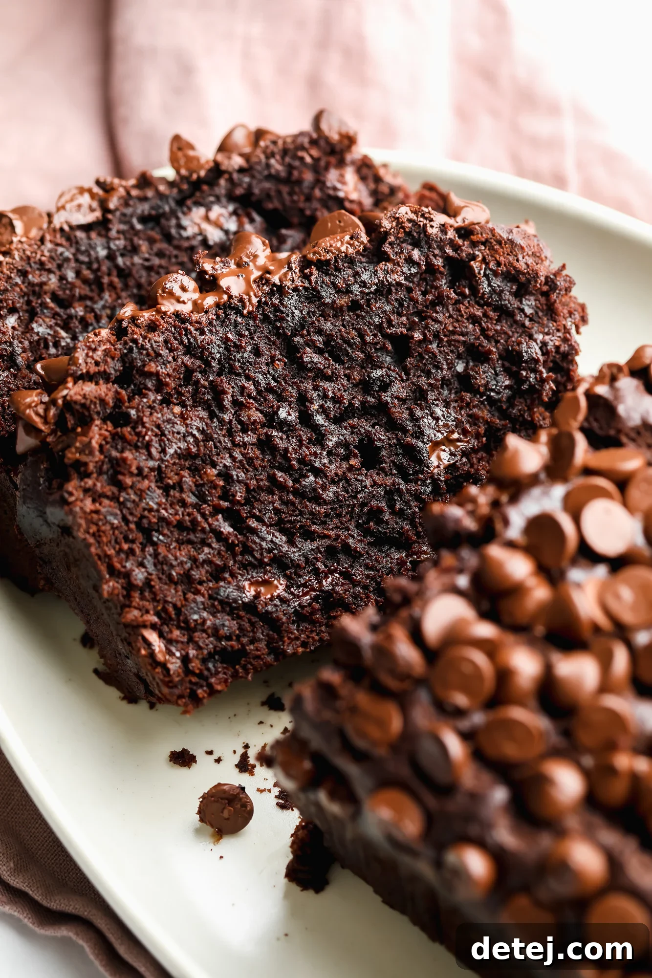 slices of chocolate banana bread on a white plate, highlighting the dense, moist crumb.