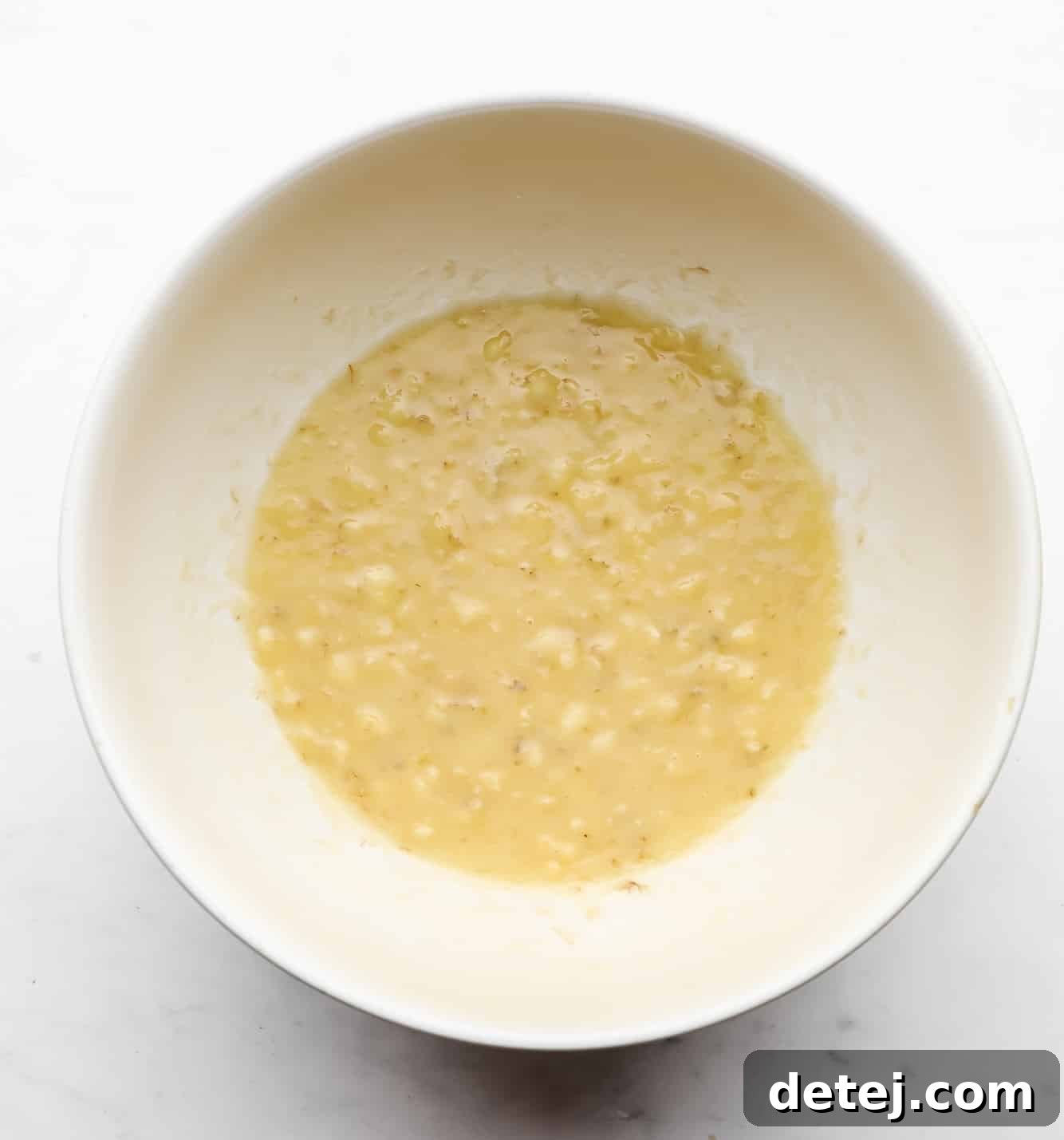 mashed bananas in a white bowl, ready for mixing.