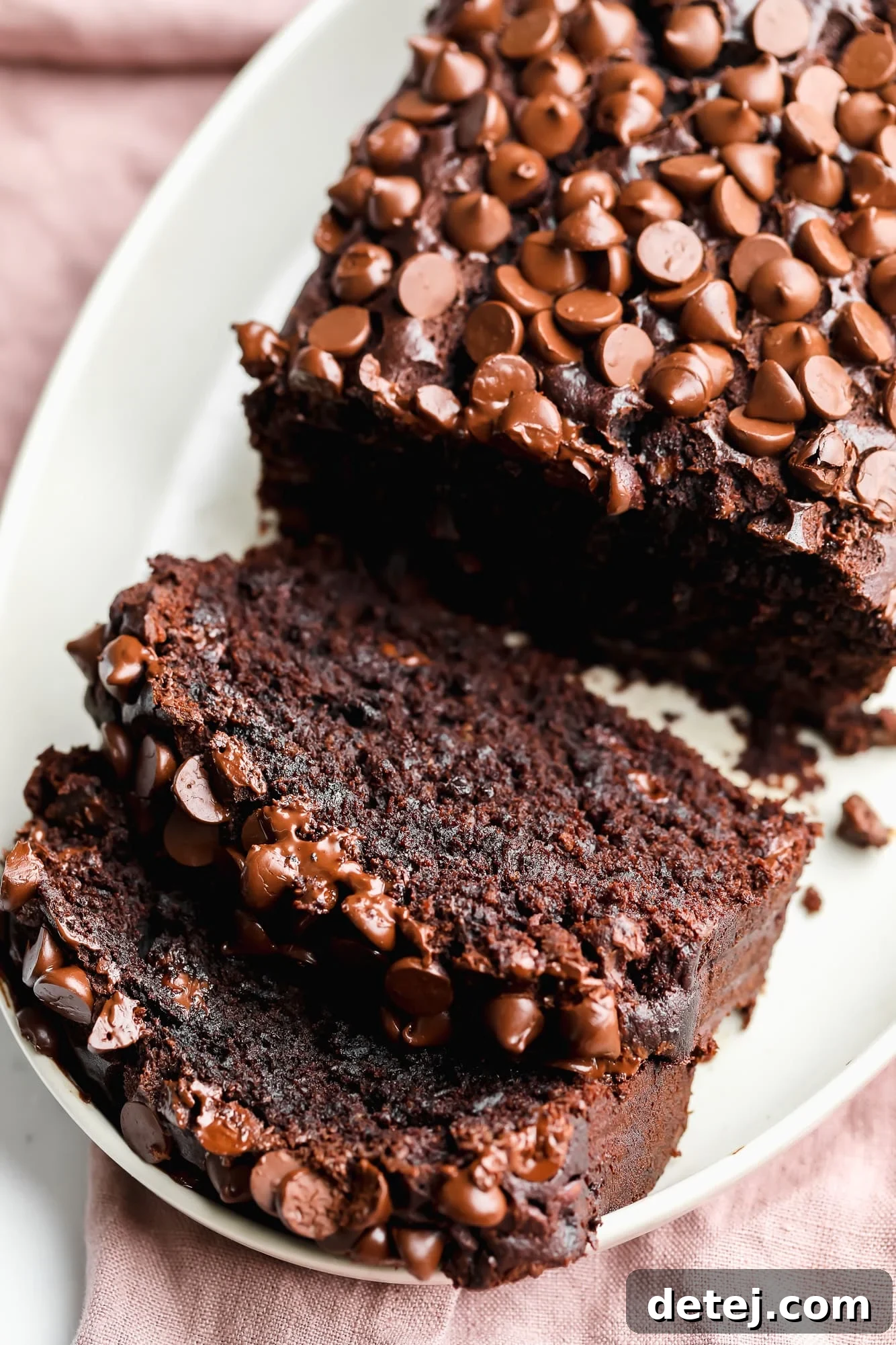 a sliced loaf of vegan chocolate banana bread on a white plate, invitingly arranged.
