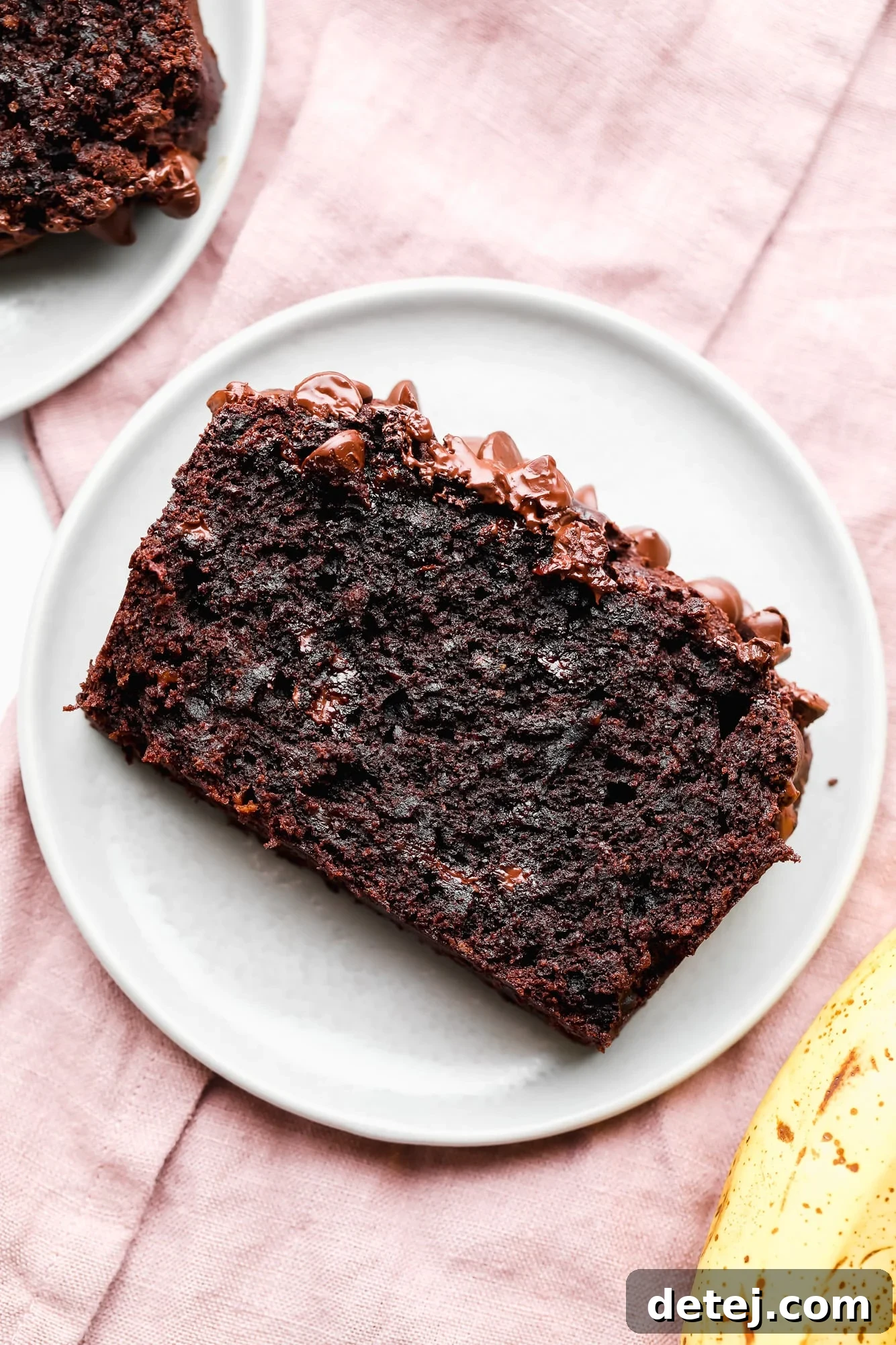 a perfect slice of vegan chocolate banana bread on a white plate, invitingly close-up.