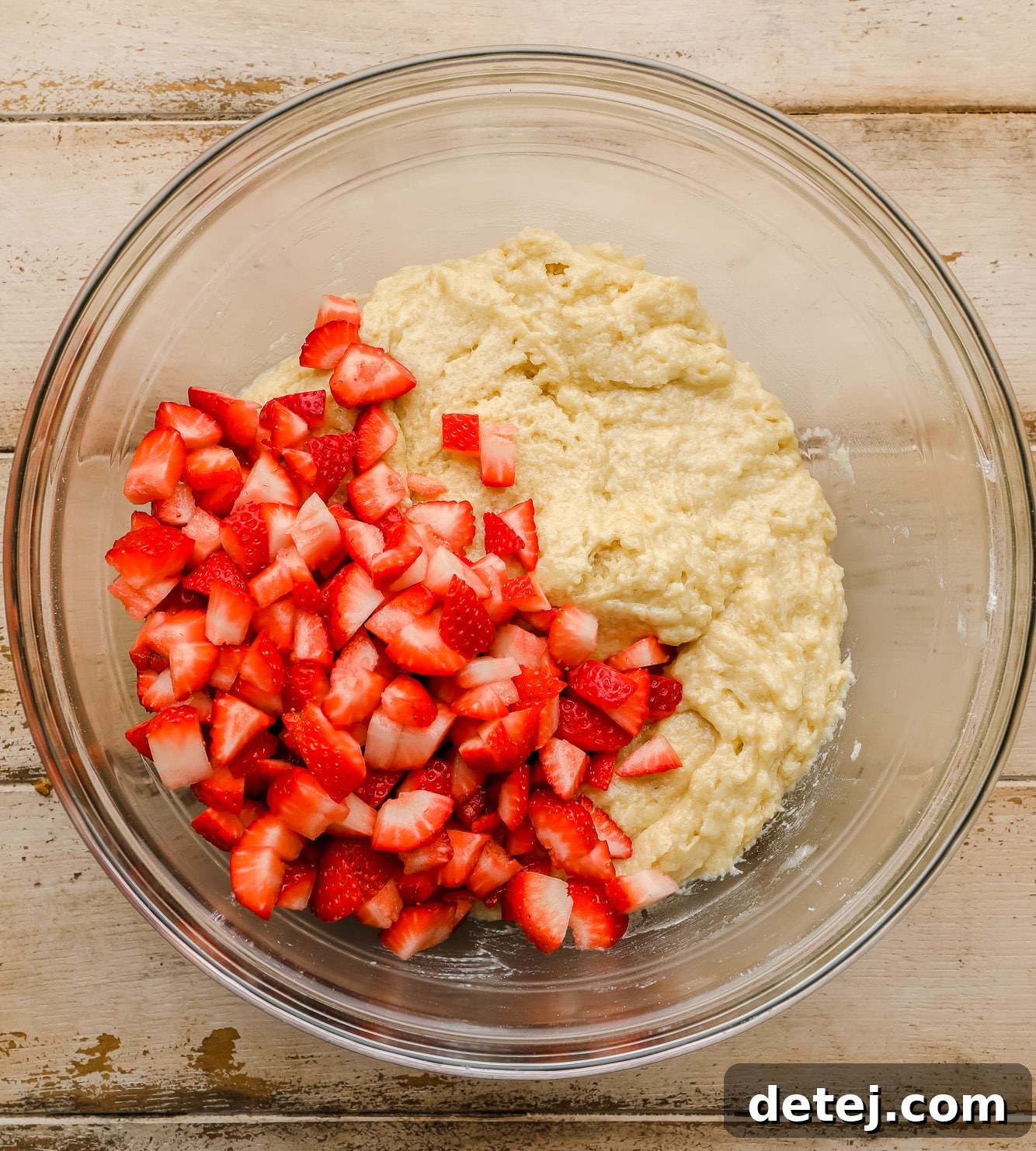 Luscious Vegan Strawberry Muffins 4 Chopped fresh strawberries resting on top of prepared muffin batter in a large glass mixing bowl.