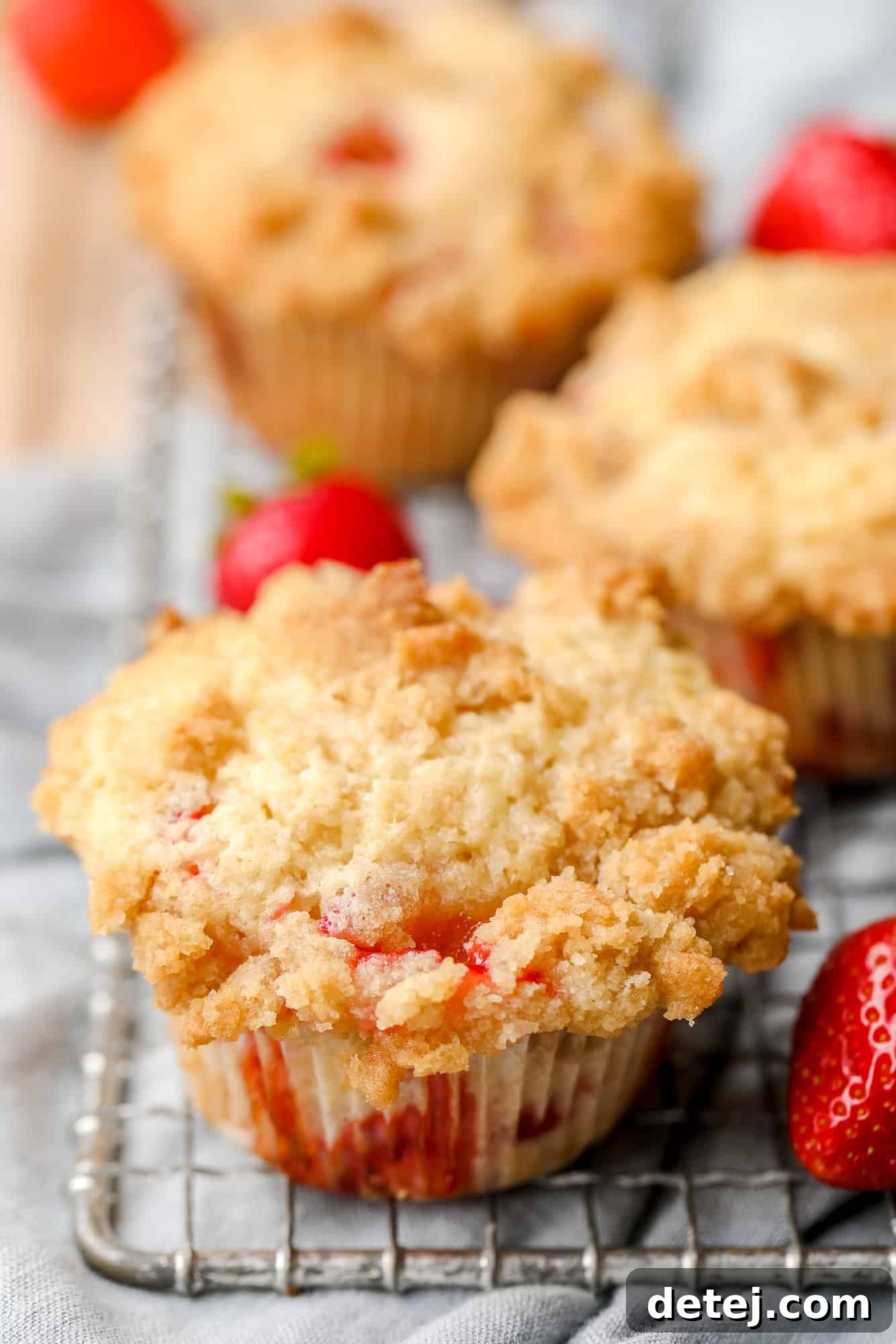 Luscious Vegan Strawberry Muffins 7 Close-up on a single baked vegan strawberry muffin with crumble topping on a wire rack.