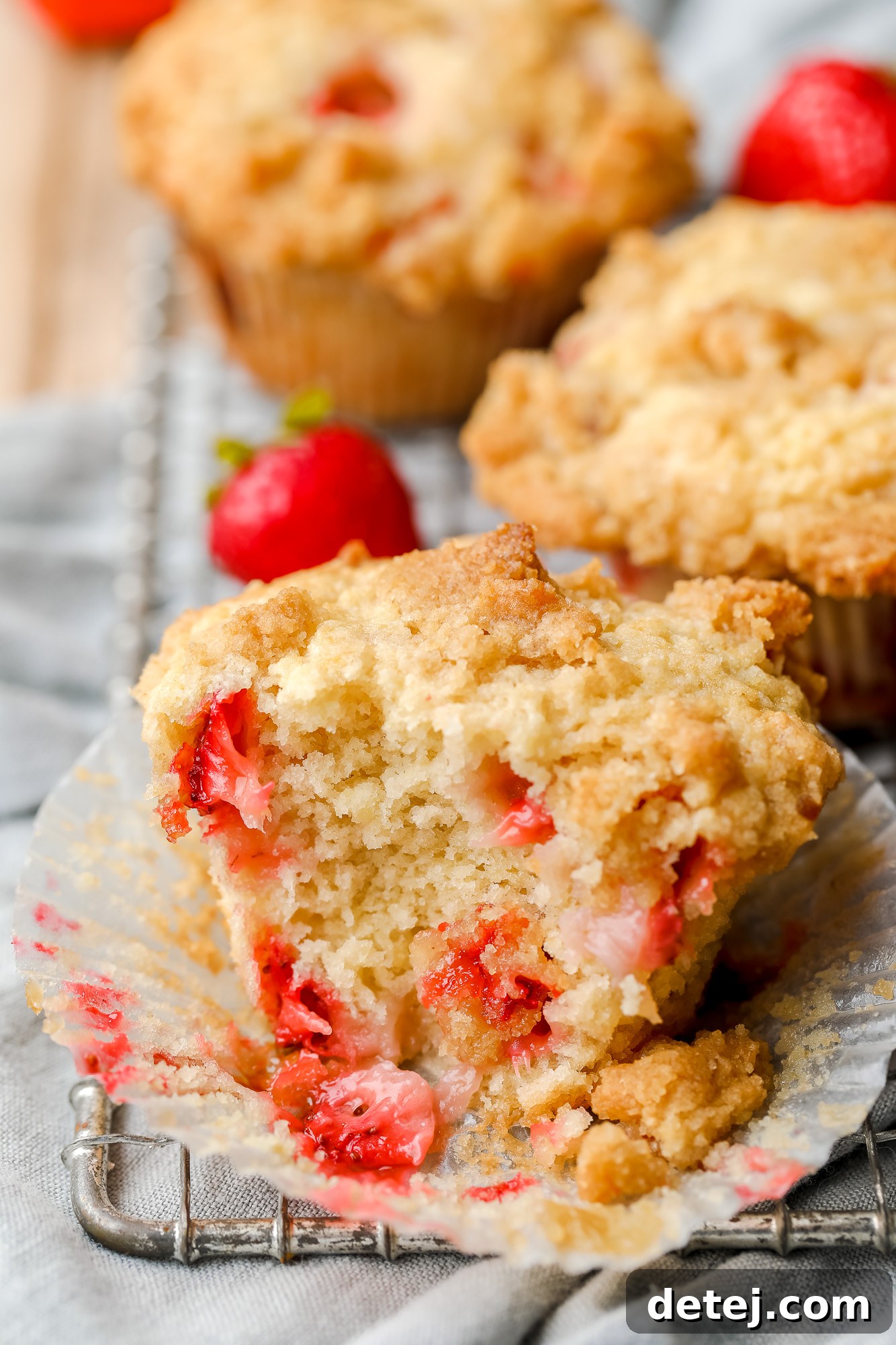 Luscious Vegan Strawberry Muffins 8 Close-up on a baked strawberry muffin that's been split in half, showcasing the fluffy texture and fruit.