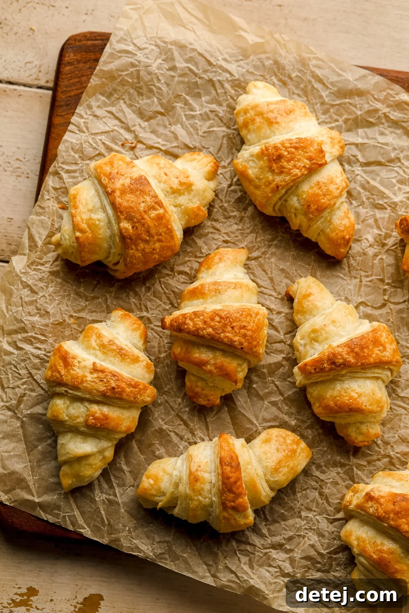 Baked vegan croissants arranged on a sheet of parchment paper, showcasing their golden color and intricate layers.