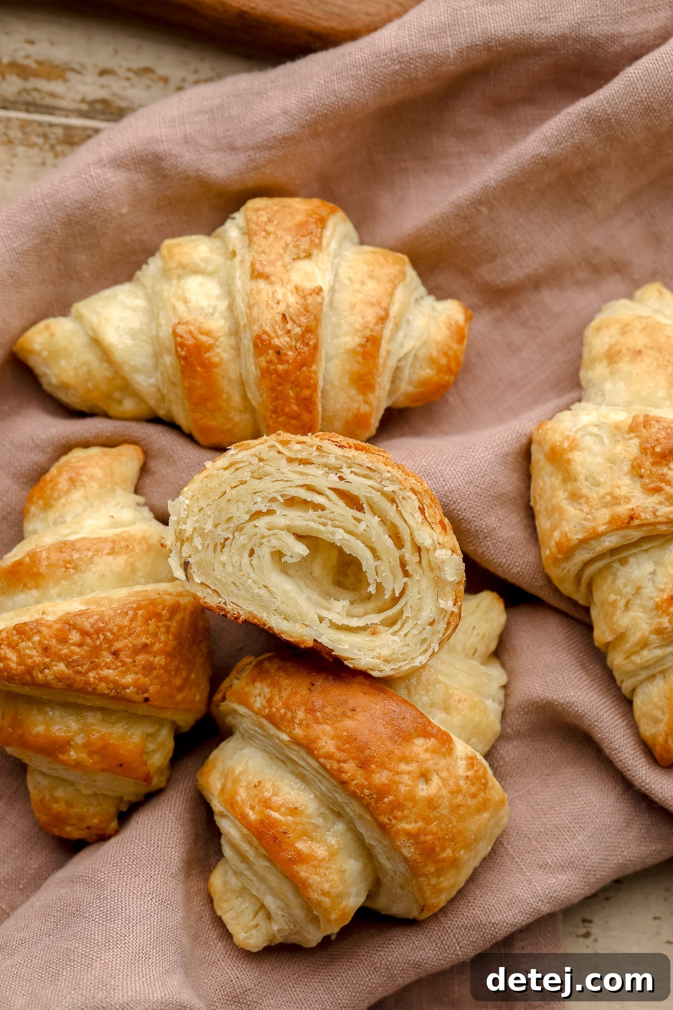 Beautifully baked vegan croissants resting on a rose-colored kitchen towel, ready to be enjoyed.