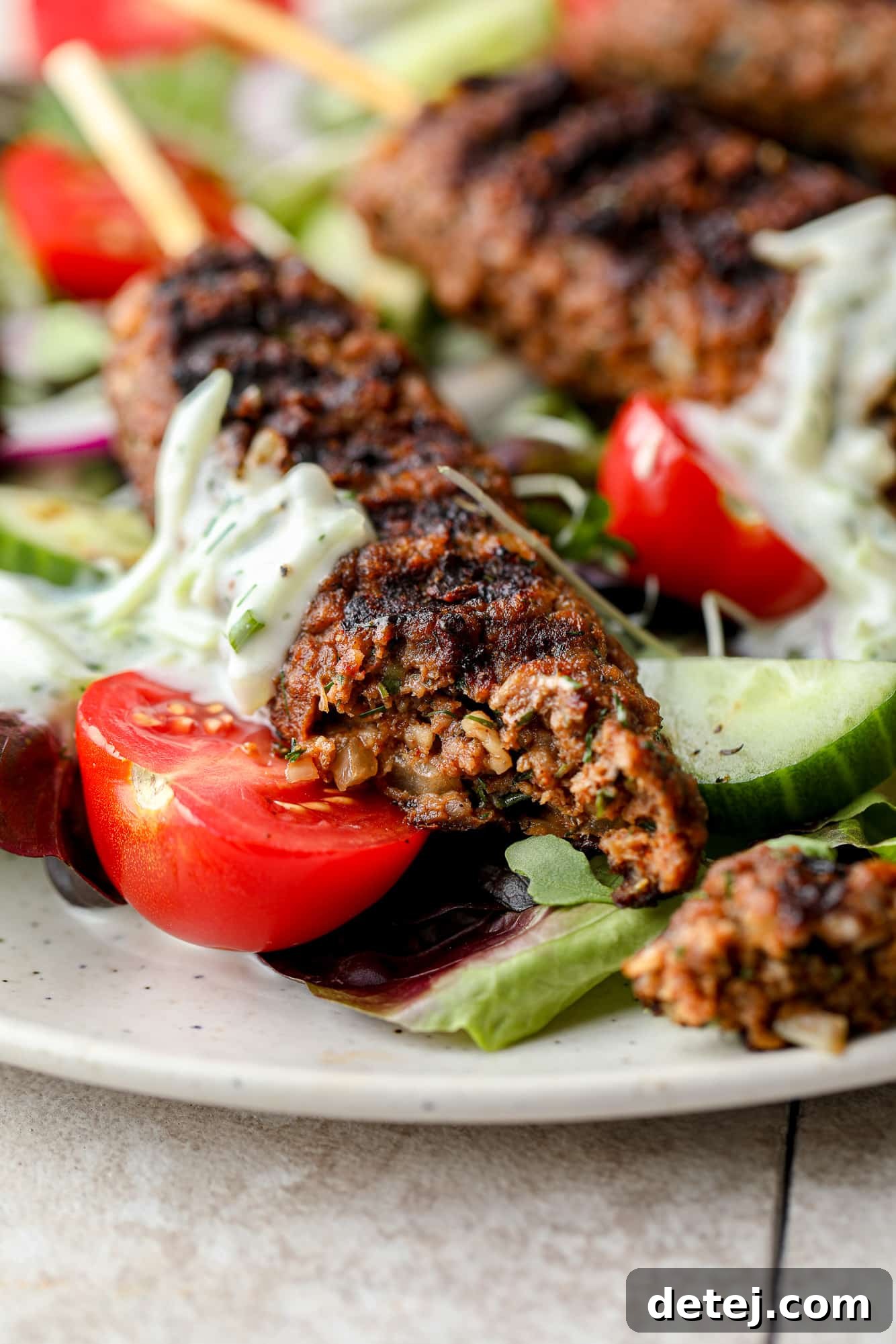 A close-up view of a vegan kofta kebab, showcasing its perfectly grilled texture and rich, spiced interior, with a bite taken out to reveal its tenderness.
