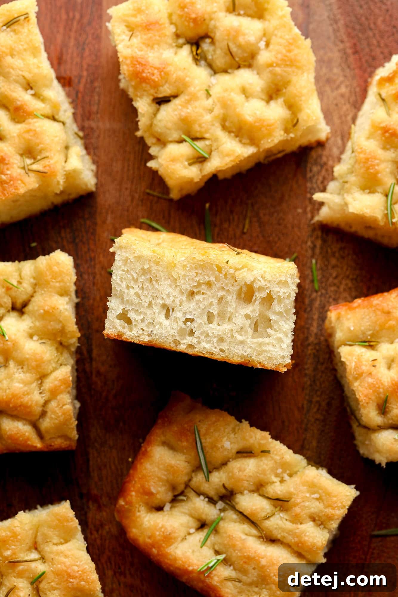 Slices of freshly baked vegan focaccia arranged on a rustic wood board, ready to be served.