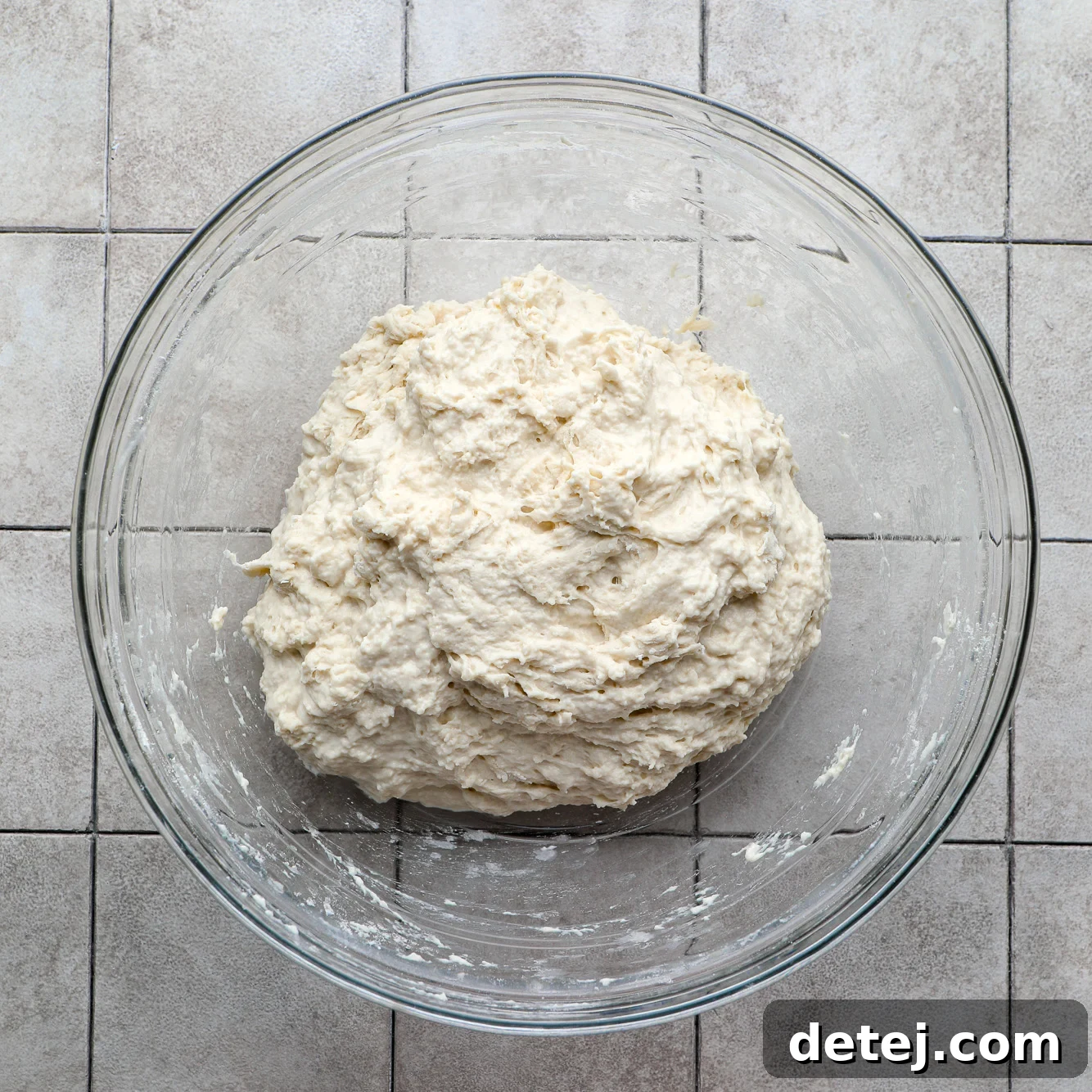 A ball of sticky focaccia dough in a glass bowl before oiling.