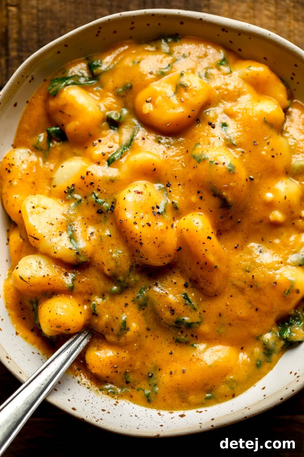 close up on a grey bowl filled with cooked pumpkin gnocchi.