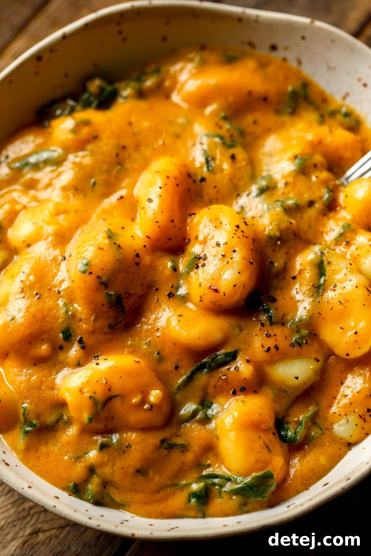 close up on a grey bowl filled with cooked pumpkin gnocchi.