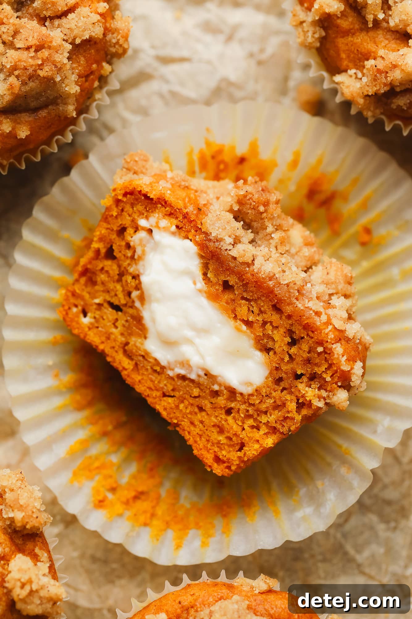 Vegan Pumpkin Cheesecake Swirl Muffins 2 a vegan pumpkin cream cheese muffin sliced in half and turned on its side, showing vegan cream cheese in the middle.
