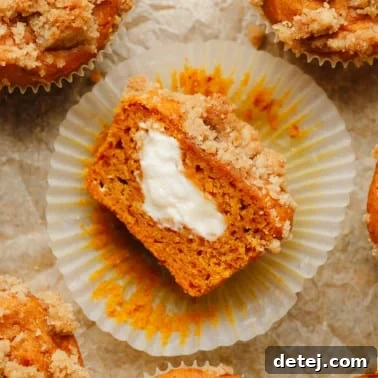 Vegan Pumpkin Cheesecake Swirl Muffins 7 a vegan pumpkin cream cheese muffin sliced in half and turned on its side, showing vegan cream cheese in the middle.