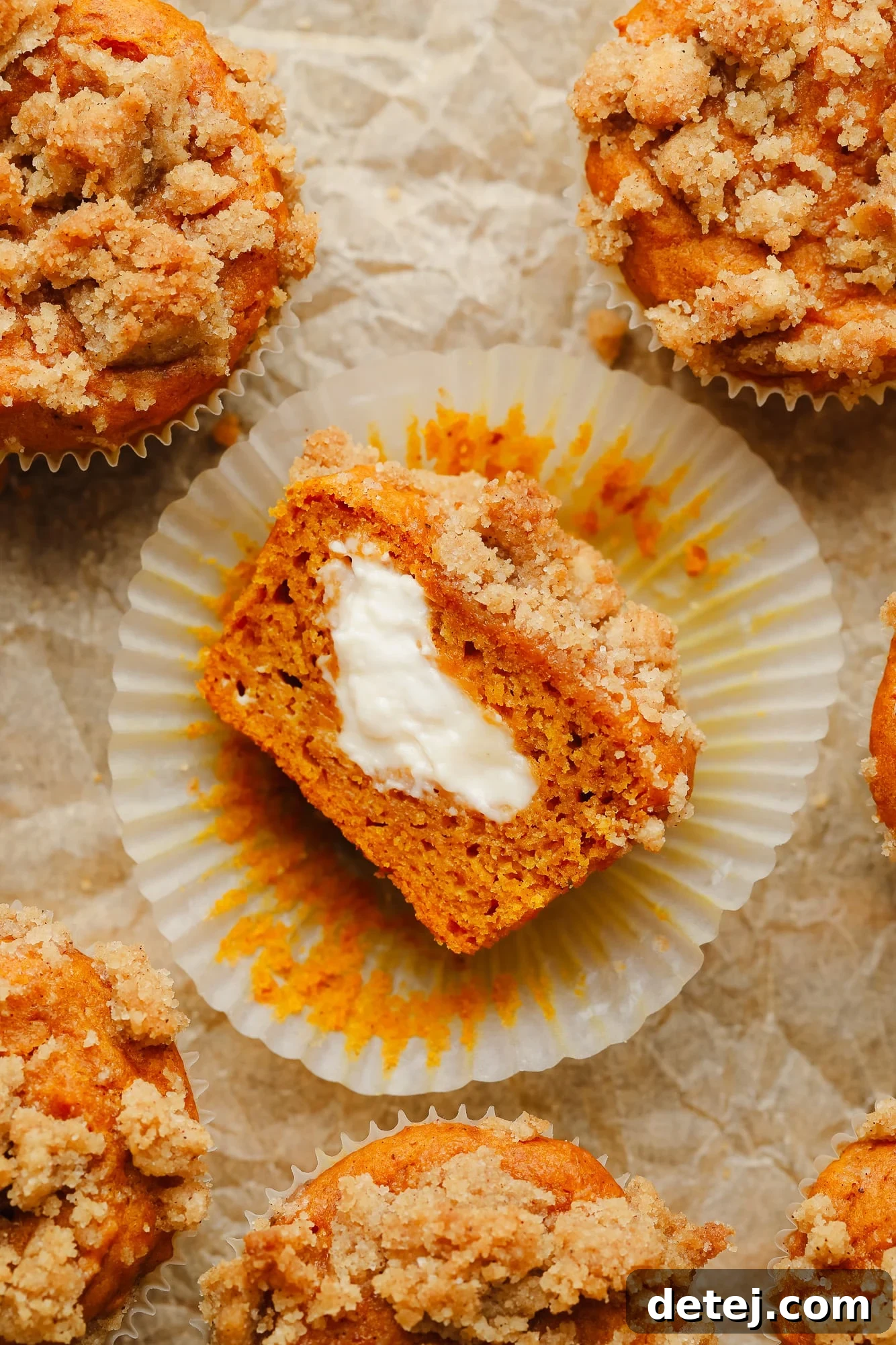Vegan Pumpkin Cheesecake Swirl Muffins 8 a vegan pumpkin cream cheese muffin sliced in half and turned on its side, showing vegan cream cheese in the middle.