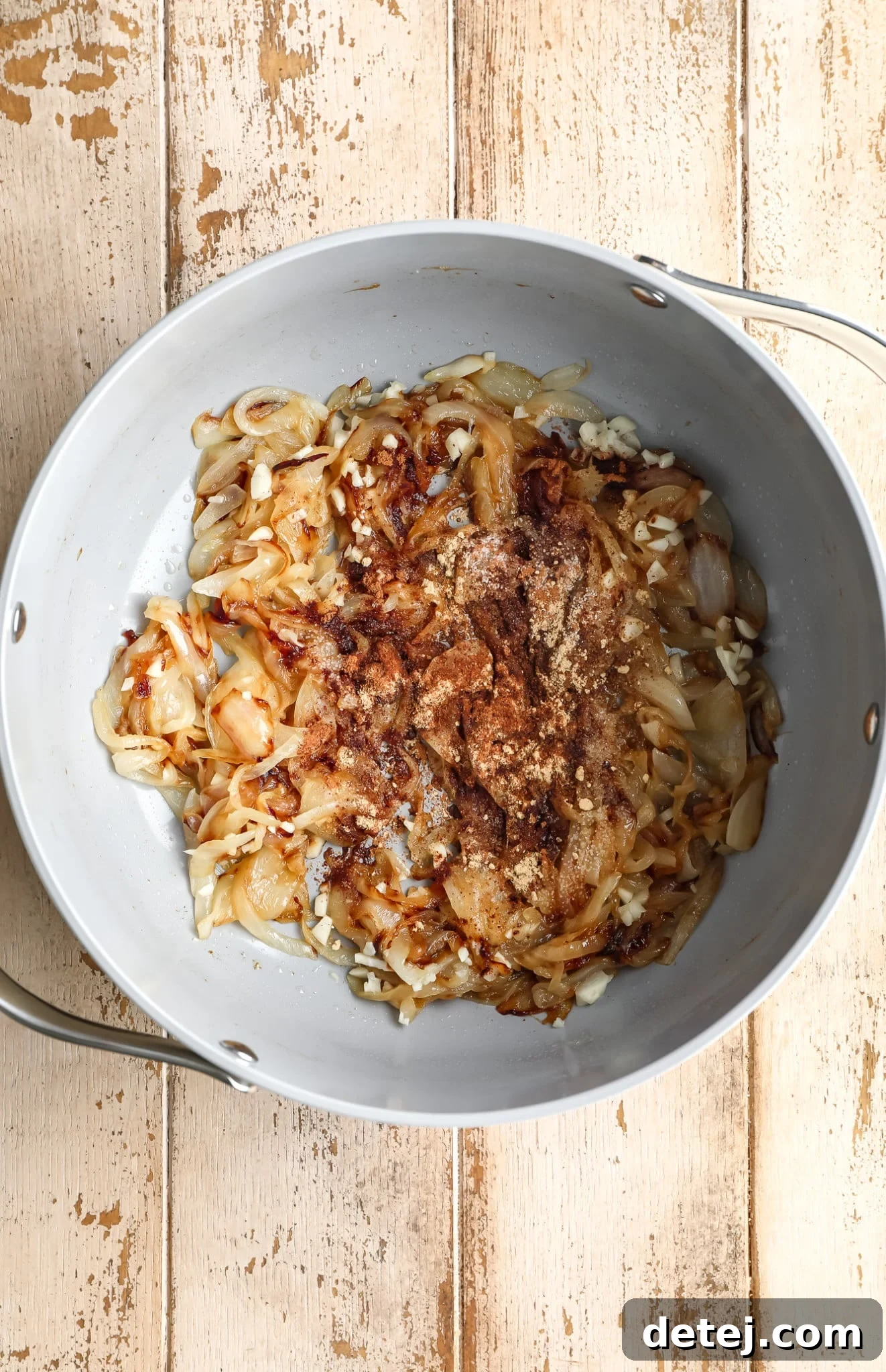Caramelized onions coated with a vibrant blend of warm spices like cinnamon, ginger, and nutmeg, ready to mingle with pumpkin.