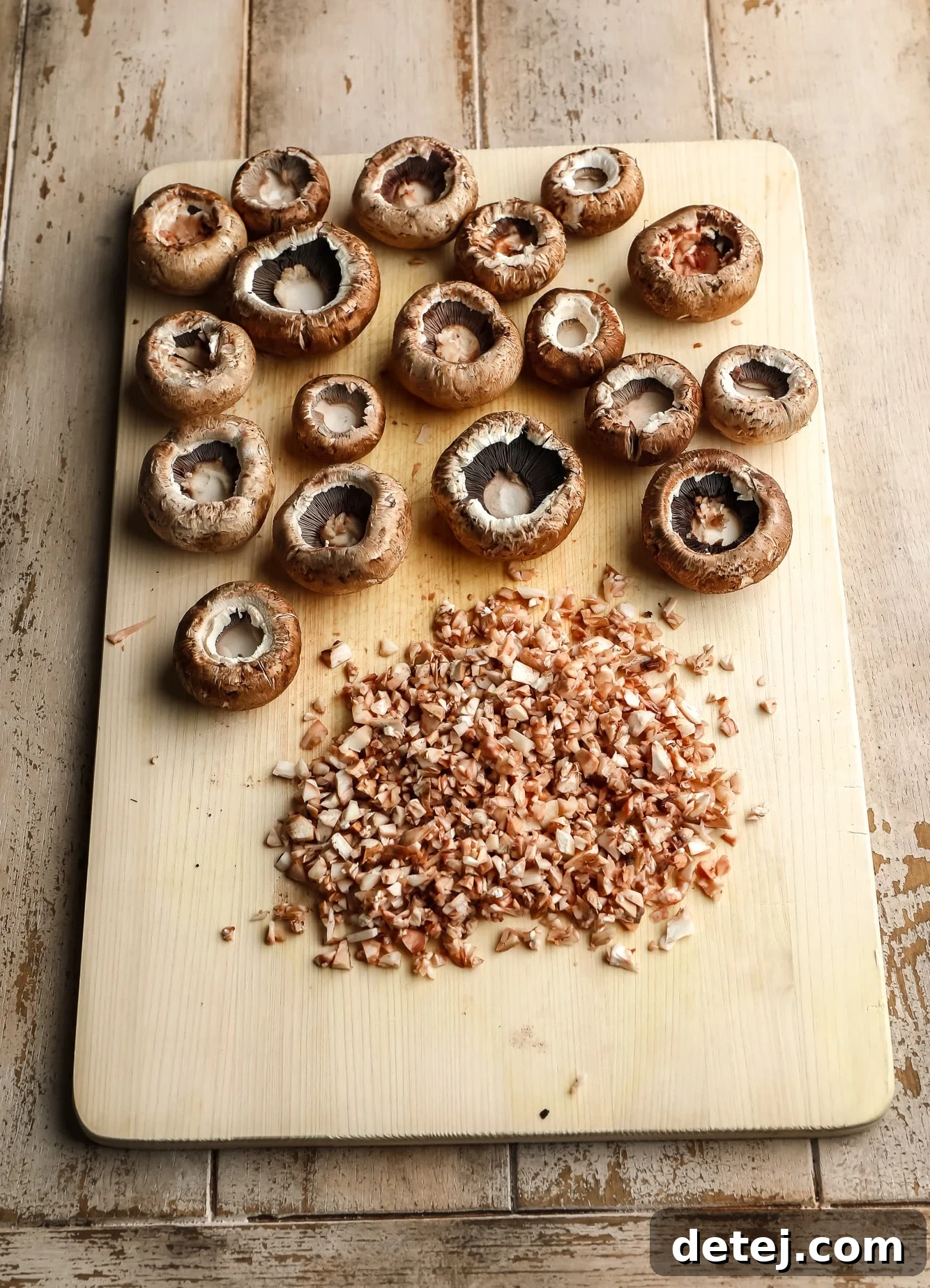Savory Vegan Mushroom Delights 3 hollow mushroom caps and diced mushroom stems on a cutting board.