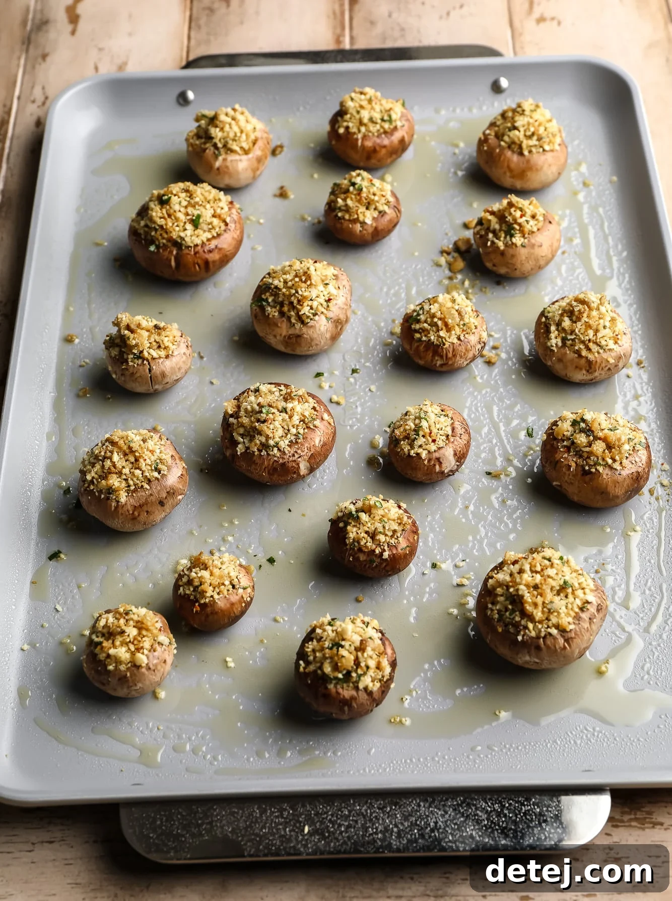 Savory Vegan Mushroom Delights 6 rows of vegan stuffed mushrooms on a greased baking sheet.