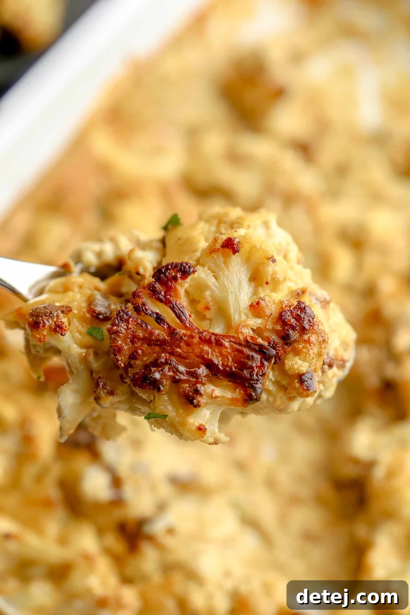 A close-up view of a roasted cauliflower floret generously smothered in creamy vegan cheese sauce, showcasing its inviting texture.