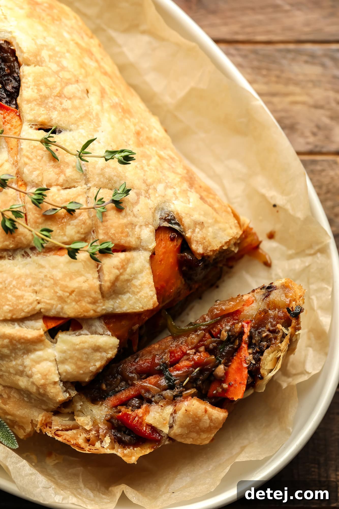A baked and sliced mushroom wellington topped with fresh thyme.