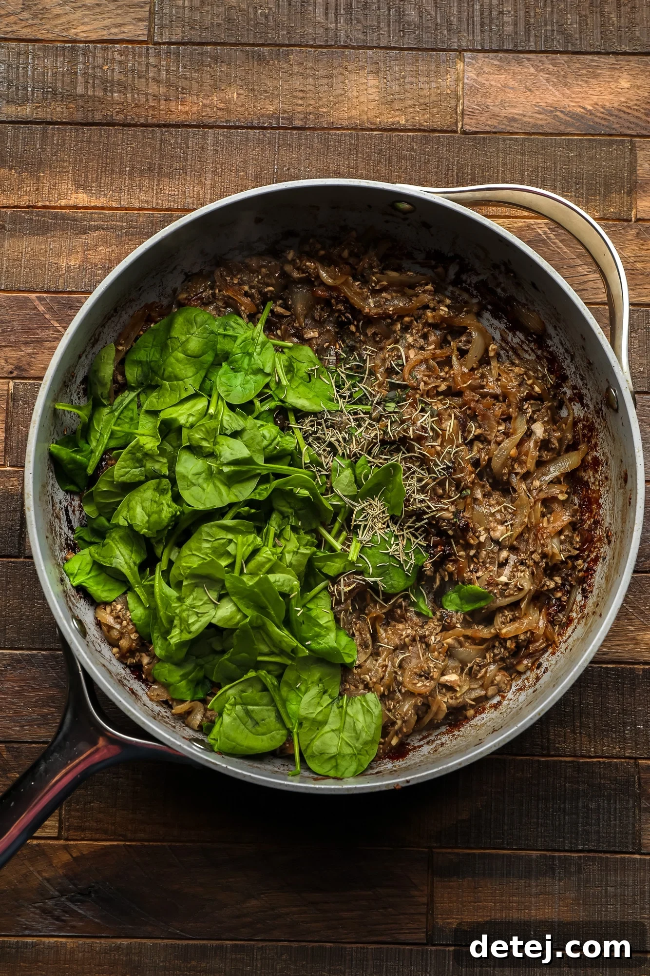 cooking the filling for a mushroom wellington in a large grey skillet.