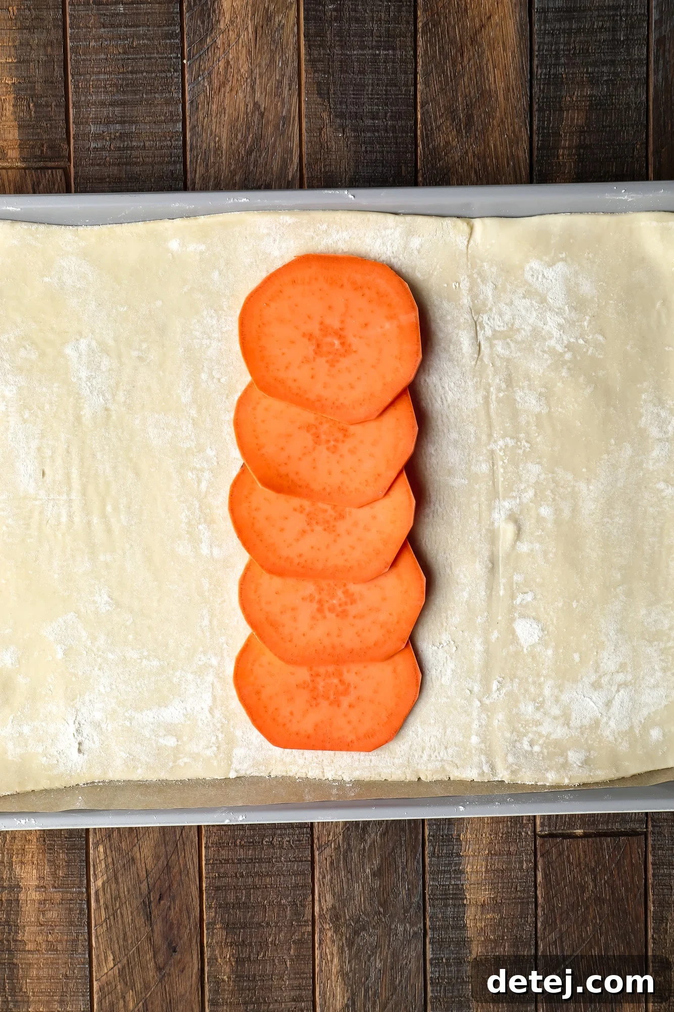 a row of sliced sweet potatoes on a sheet of puff pastry.