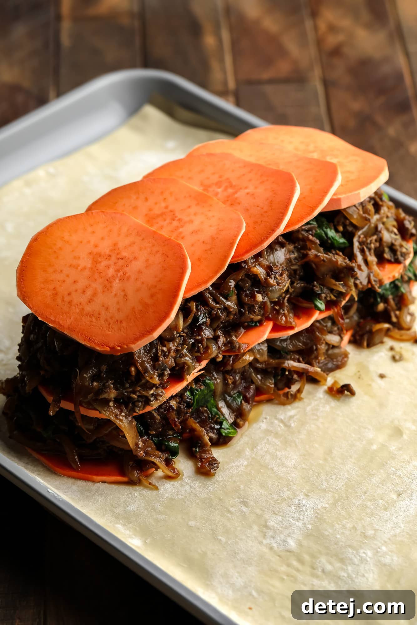 assembling the sweet potato and mushroom filling for mushroom wellington on a sheet of puff pastry.