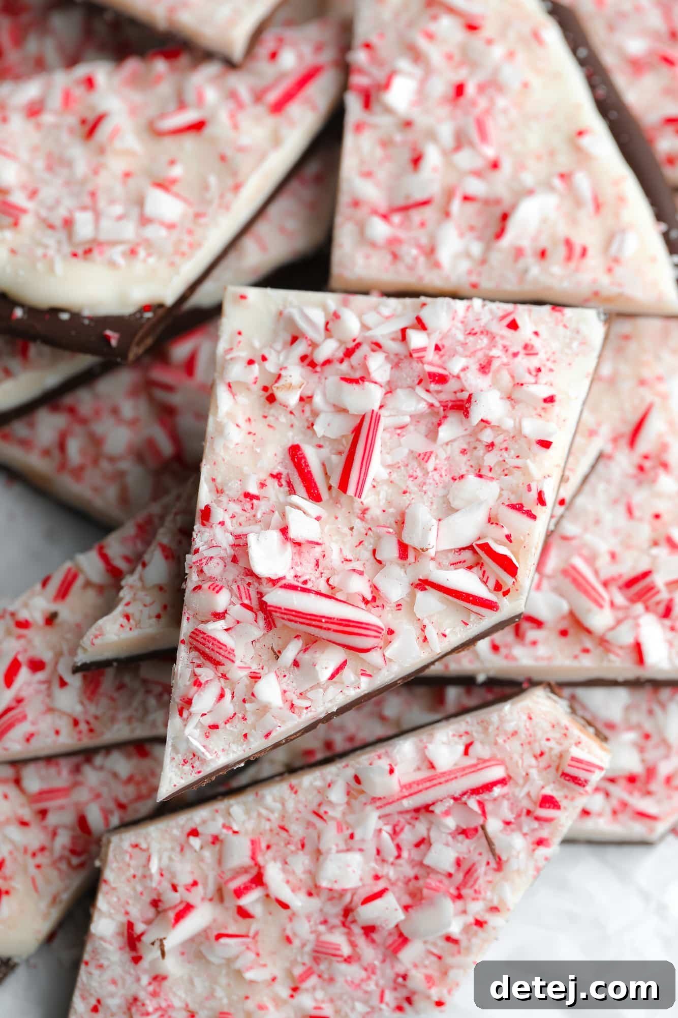A beautiful pile of broken vegan peppermint bark pieces, showcasing the vibrant layers and festive candy cane topping.
