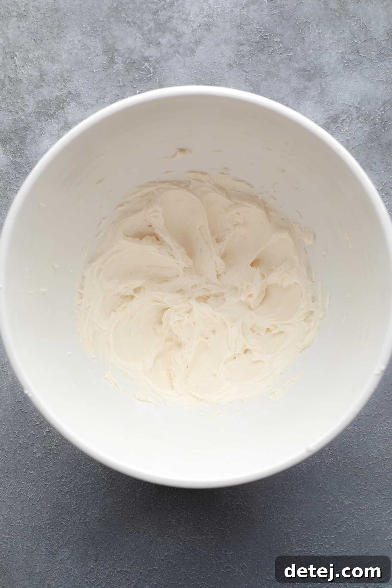 Close-up of smooth, white vegan vanilla frosting in a clean white bowl.