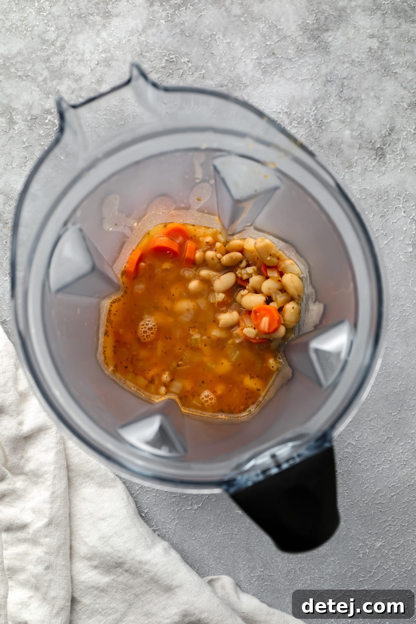 A portion of the white bean soup being blended in a high-speed blender to create a creamy texture.