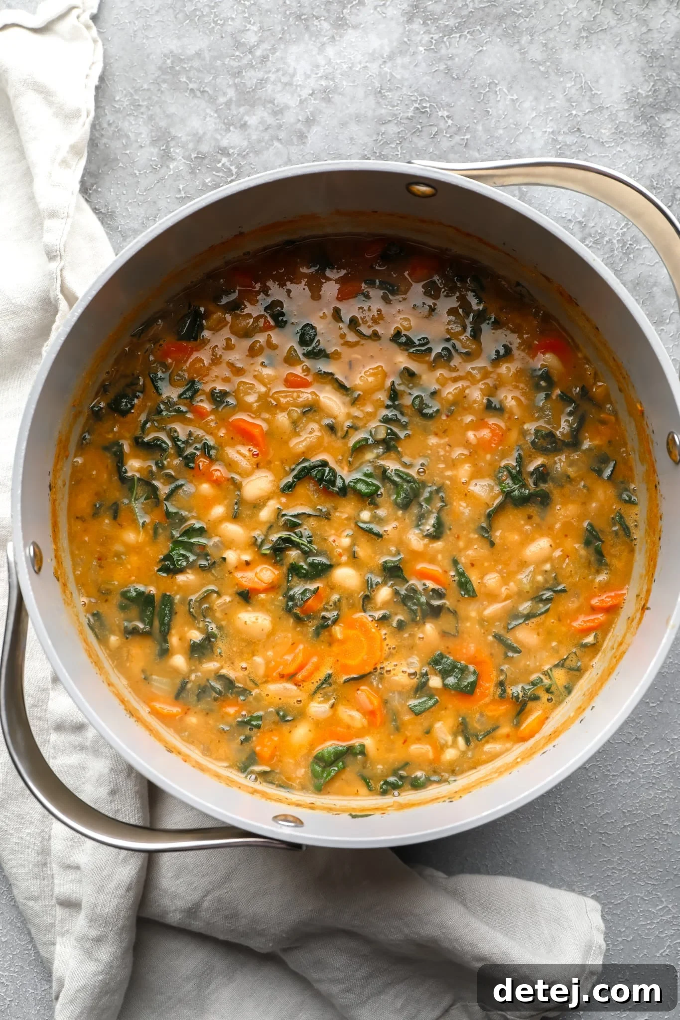 A large grey pot filled with cooked white bean soup, ready to be served.