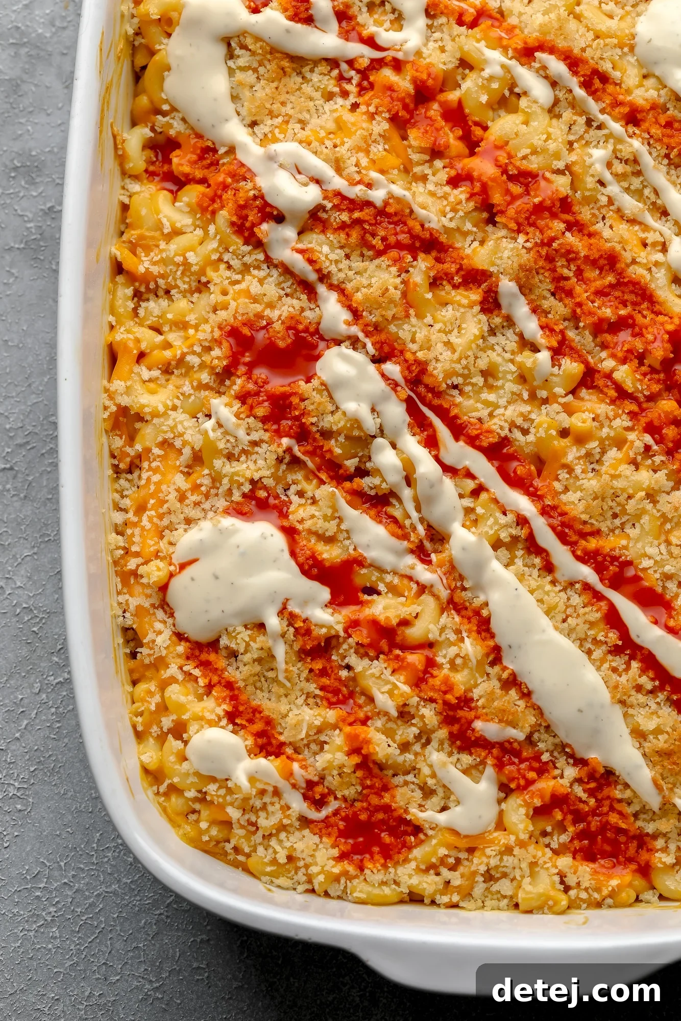 Creamy Vegan Buffalo Mac and Cheeze 6 baked vegan buffalo mac and cheese topped with drizzles of white vegan ranch and red hot sauce.
