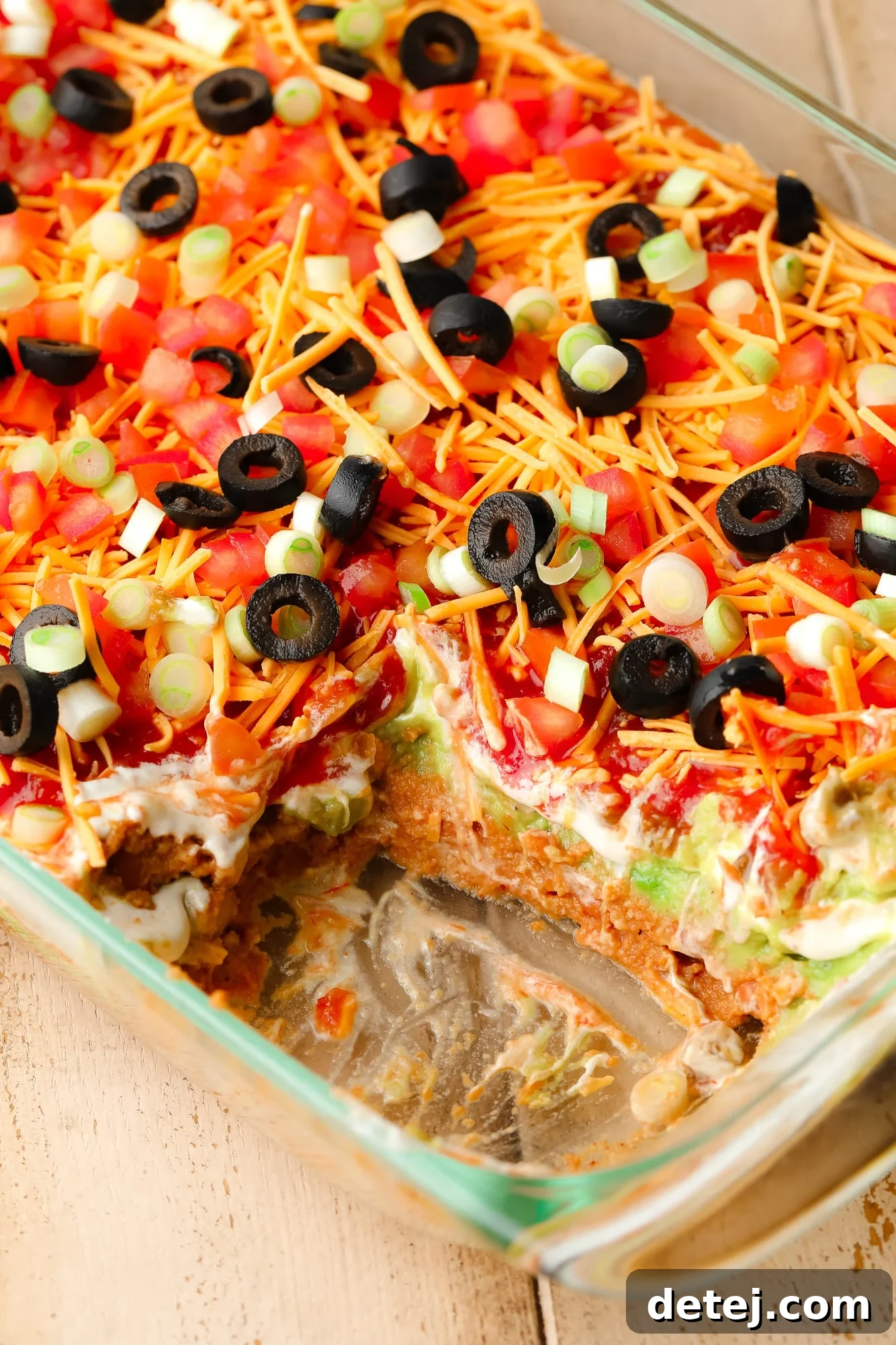 close up on a vegan 7 layer dip in a glass dish.