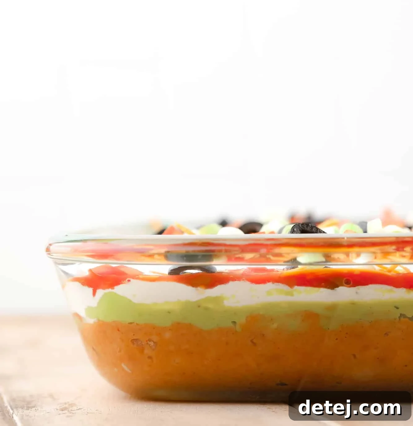 side view of vegan 7 layer dip in a glass dish.