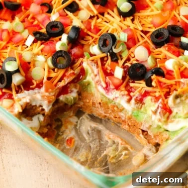 close up on a vegan 7 layer dip in a glass dish.
