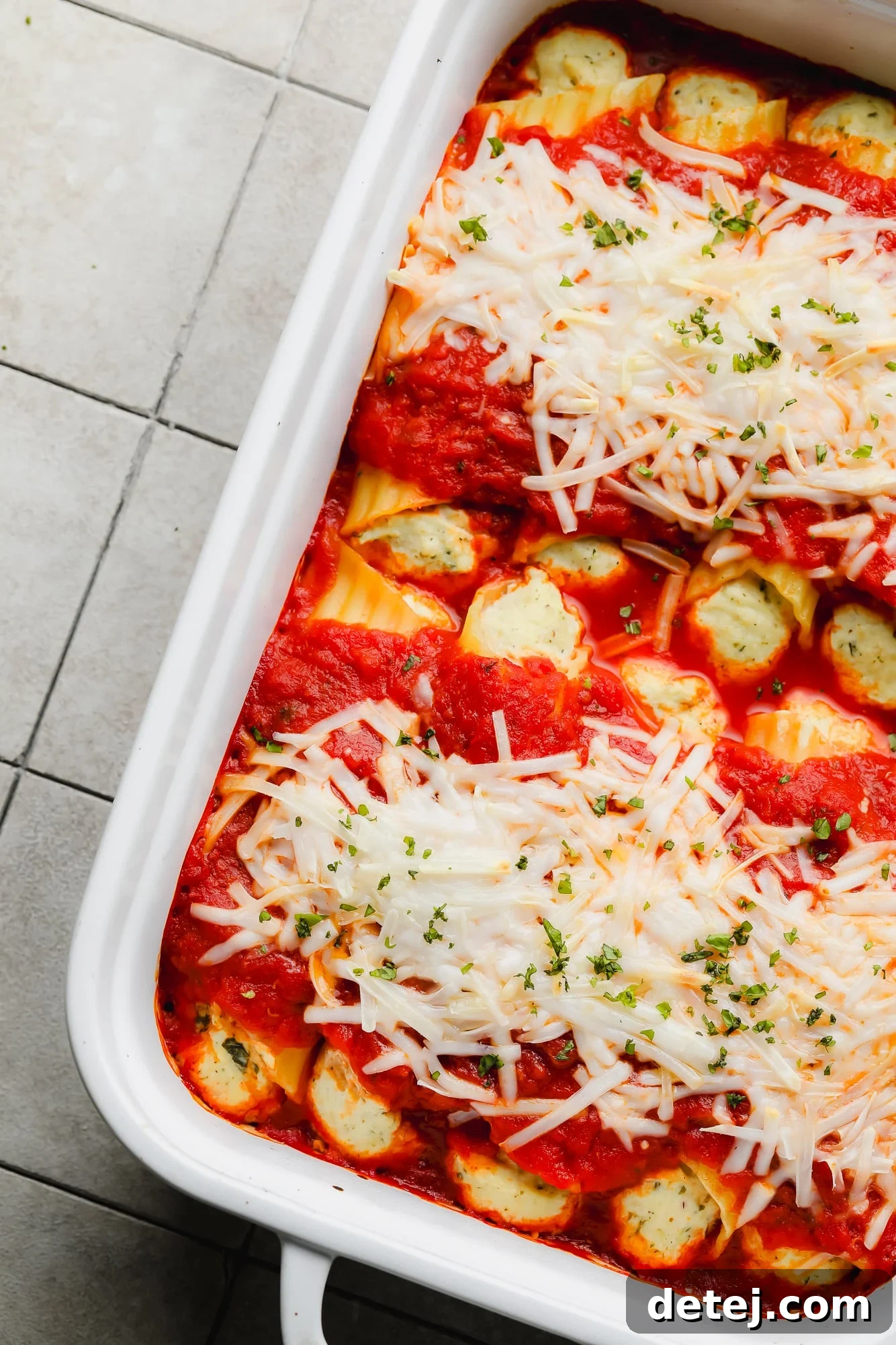 Plant-Based Manicotti 2 baked vegan manicotti topped with marinara sauce and vegan mozzarella in a white baking dish.