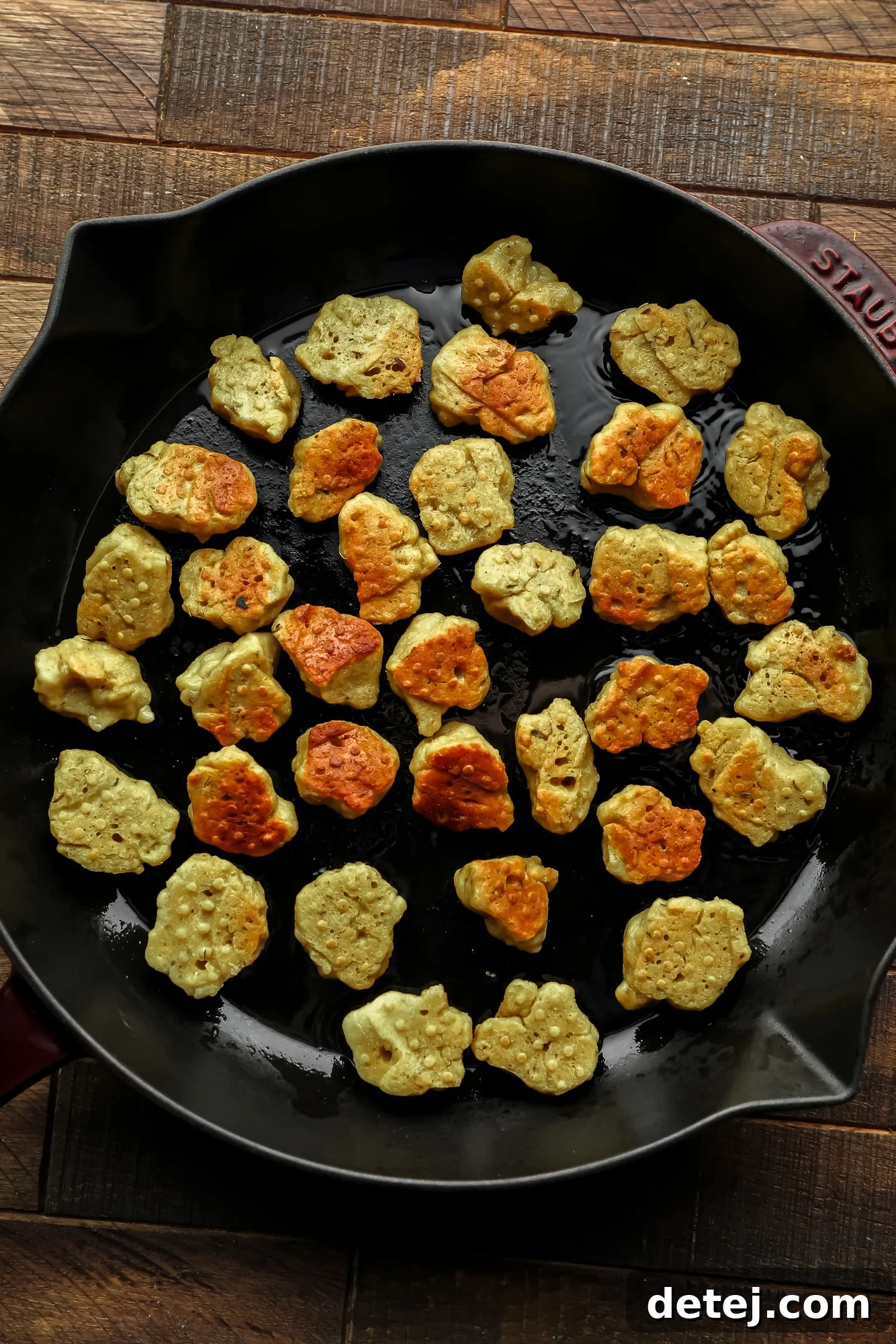 Effortless Seitan 7 frying seitan nuggets in a large black skillet.