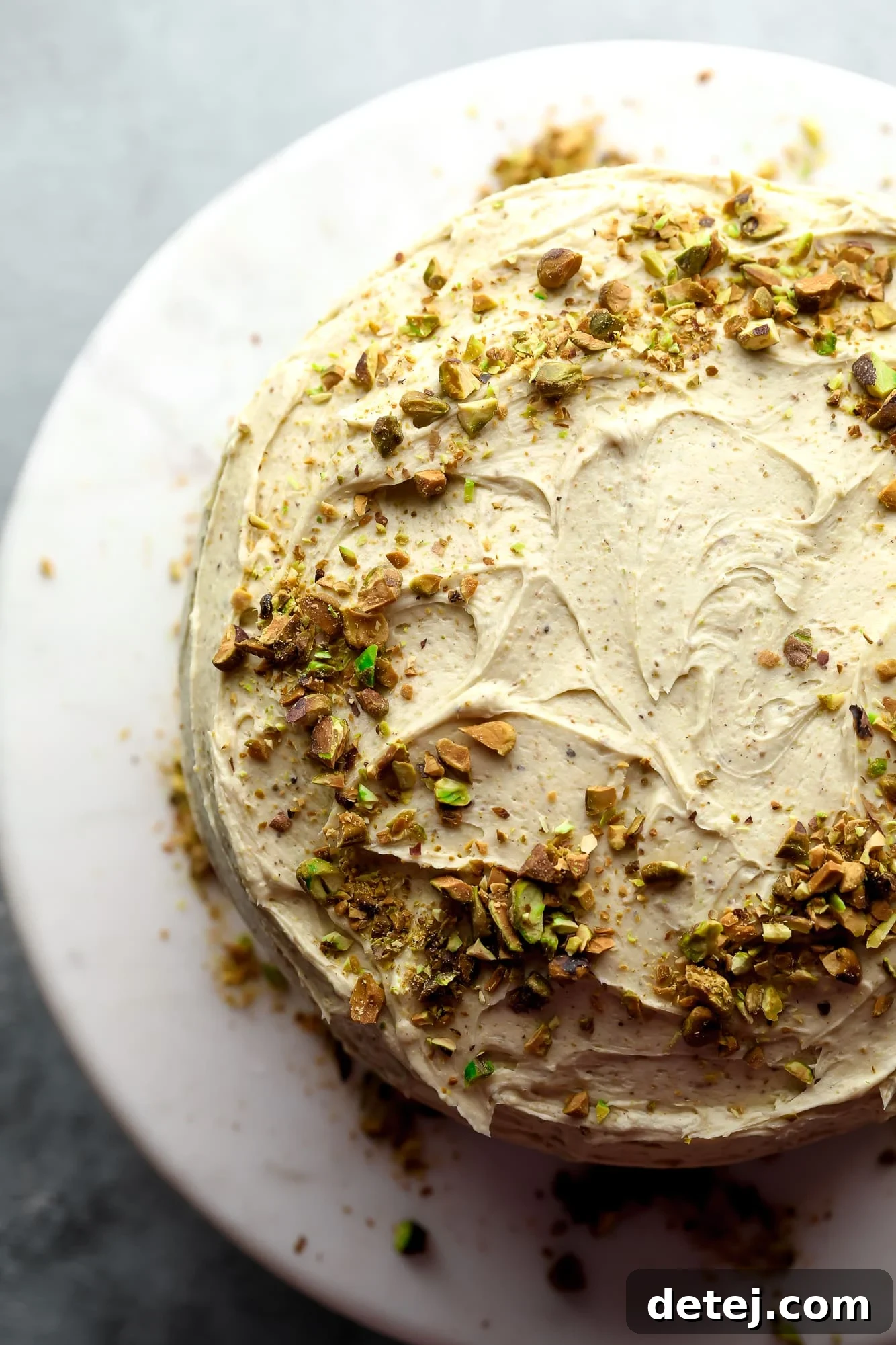 vegan pistachio cake decorated with pistachio frosting and crushed pistachios.