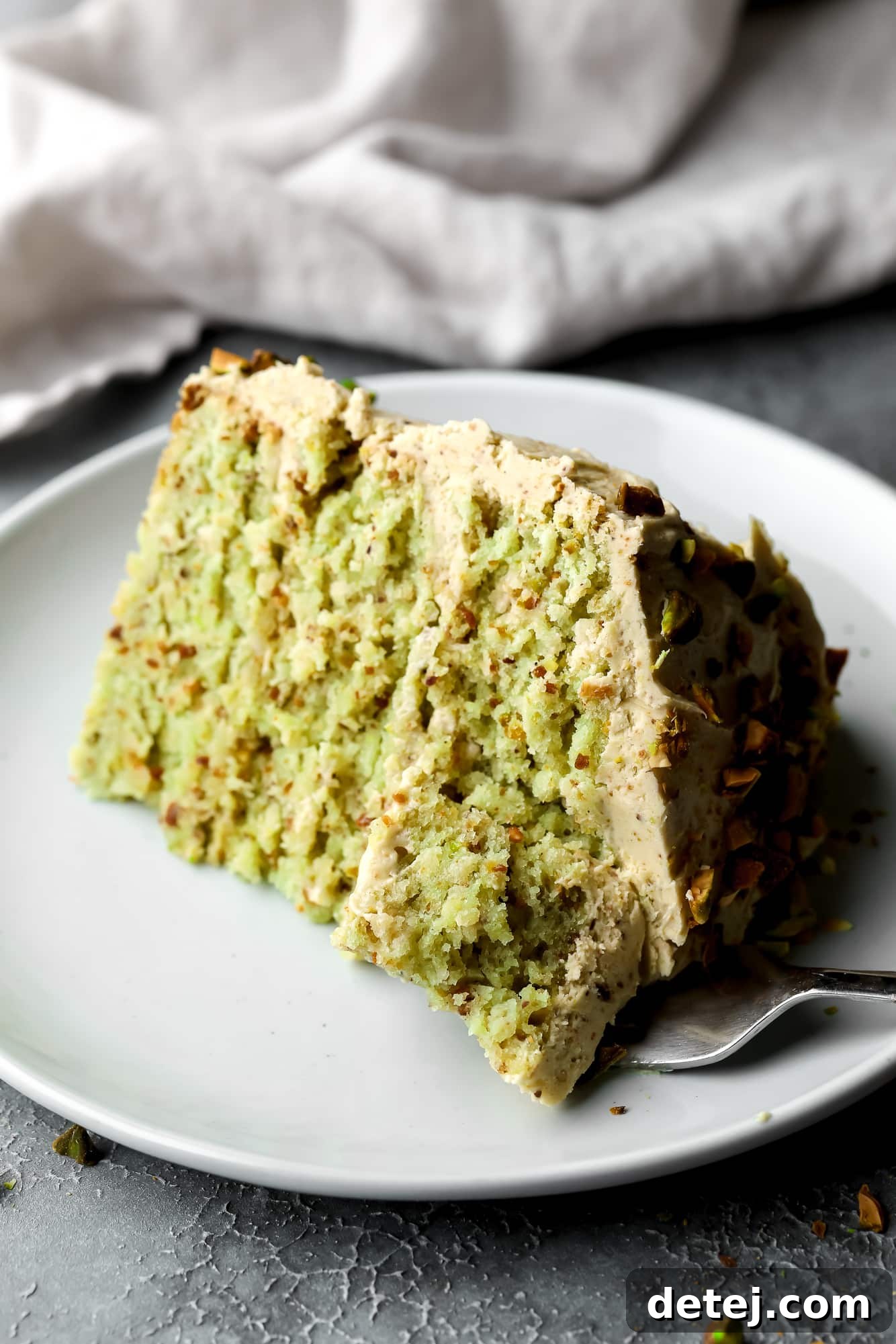 a slice of vegan pistachio cake on a white plate.