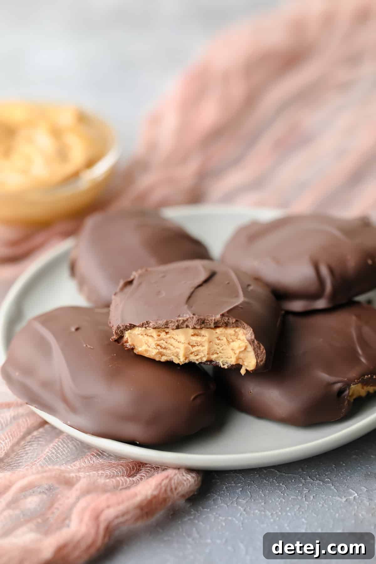 A bite taken out of a vegan peanut butter egg on a grey plate, with more eggs arranged around it.