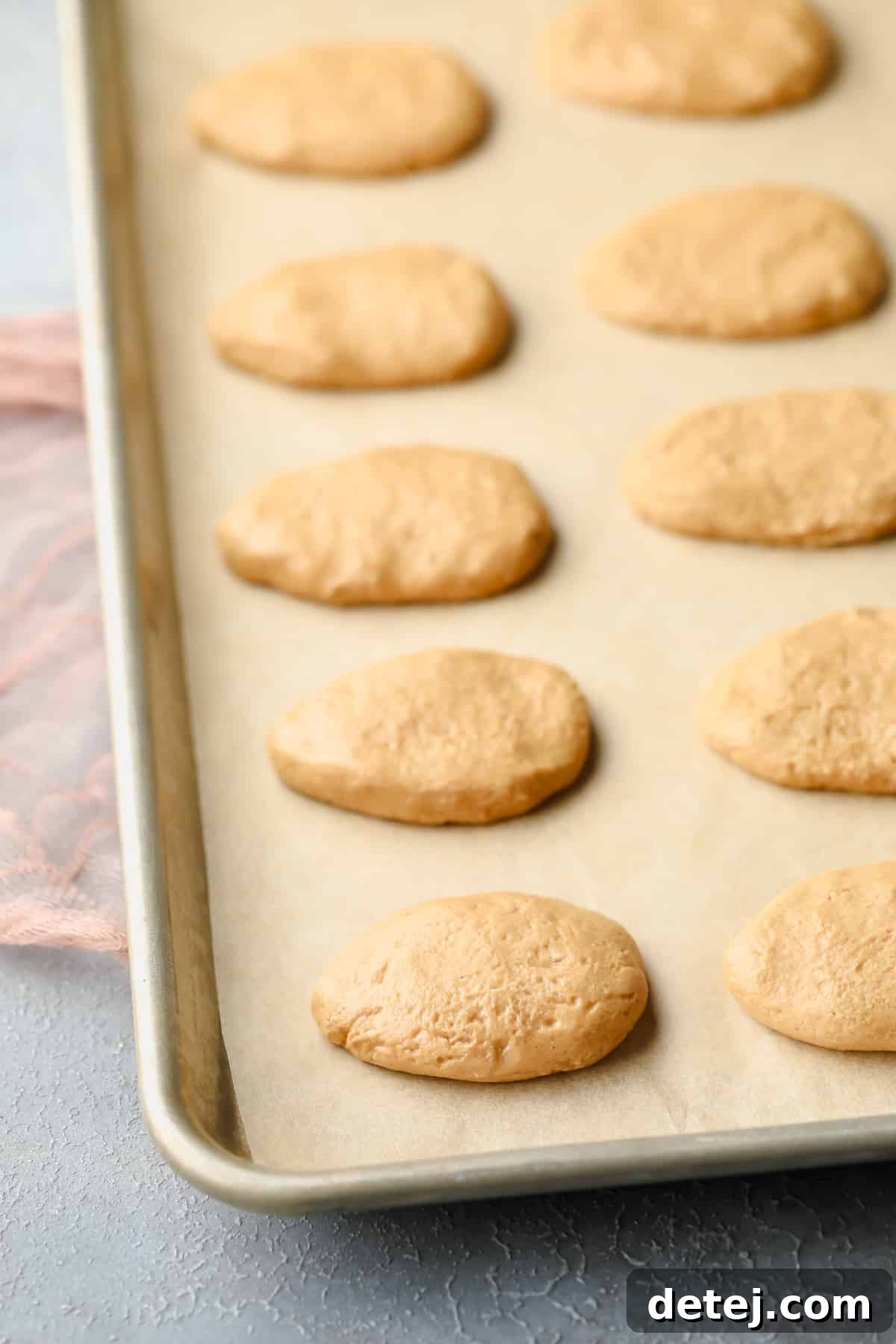 A baking sheet filled with perfectly shaped peanut butter egg forms, ready for their chocolate coating.