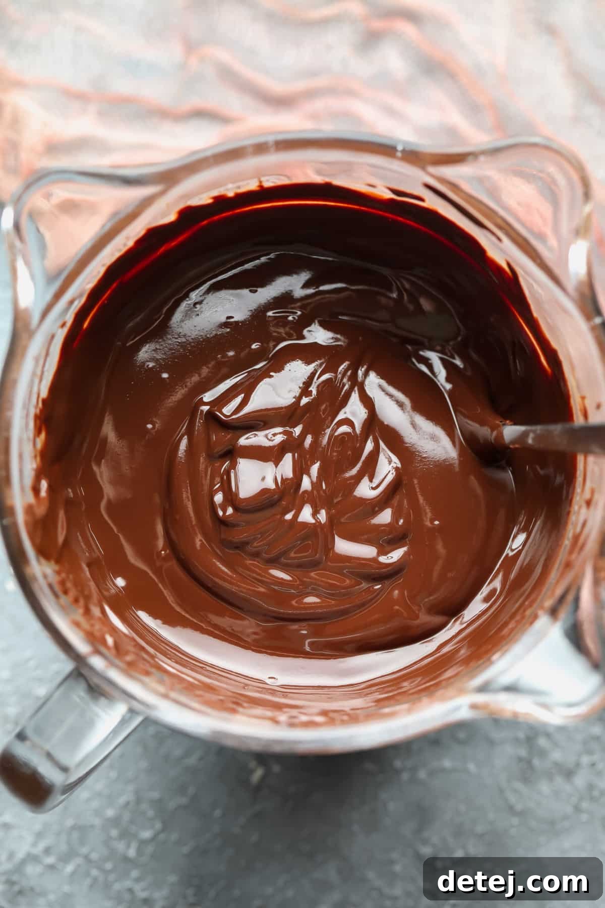 Melted chocolate in a clear glass bowl, smooth and ready for dipping.