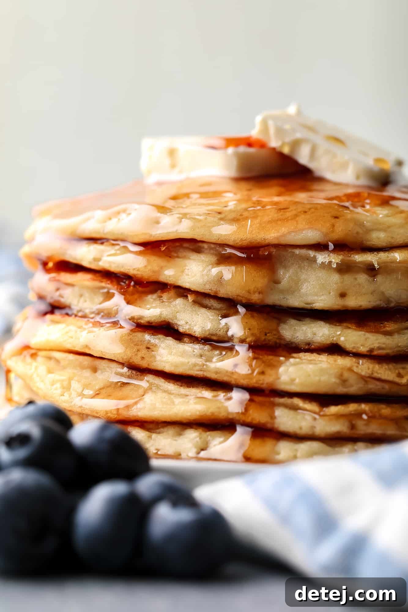 a stack of vegan protein pancakes topped with maple syrup and banana slices.