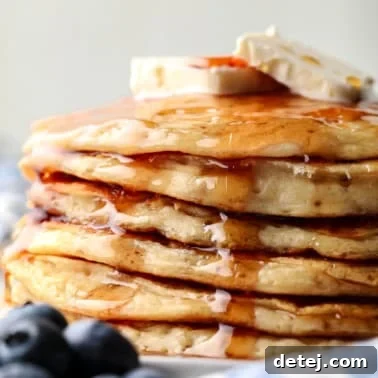 a stack of vegan protein pancakes topped with maple syrup and banana slices.