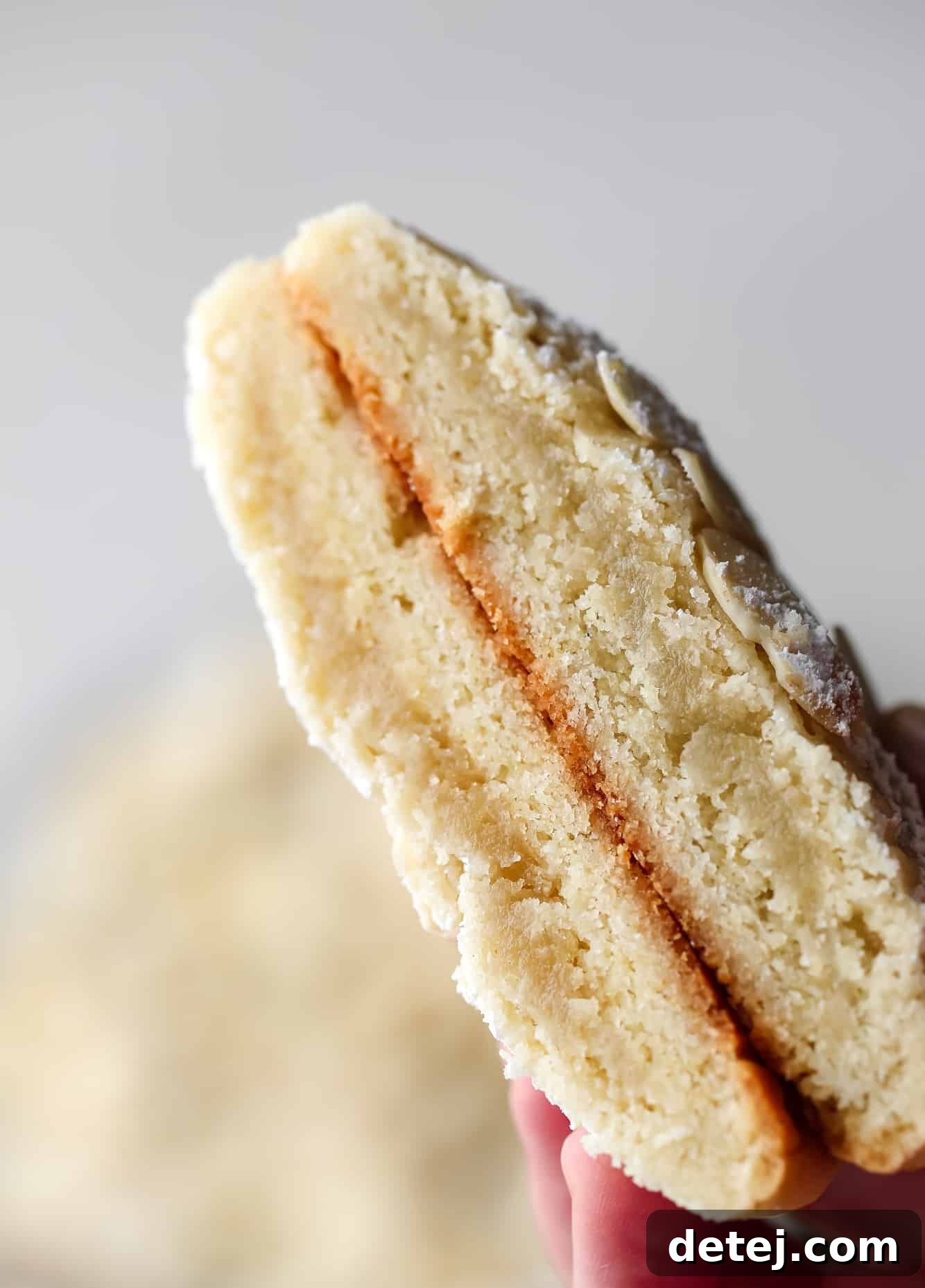 Close up of a Vegan Almond Croissant Cookie cut in half, revealing the rich, buttery almond frangipane filling inside.