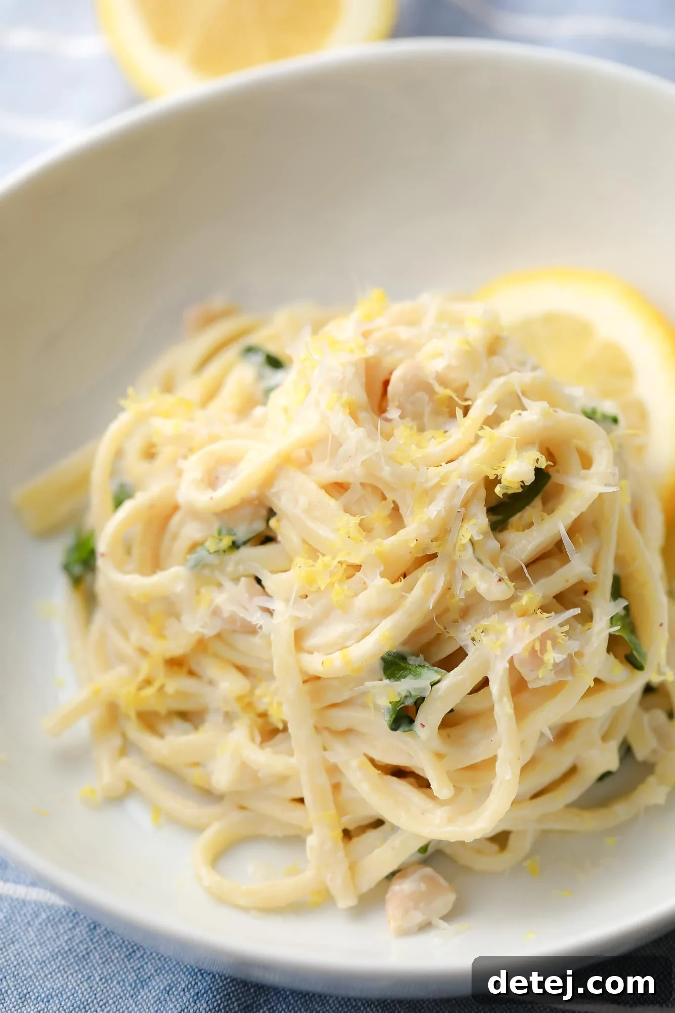 close up on creamy lemon pasta in a white bowl.