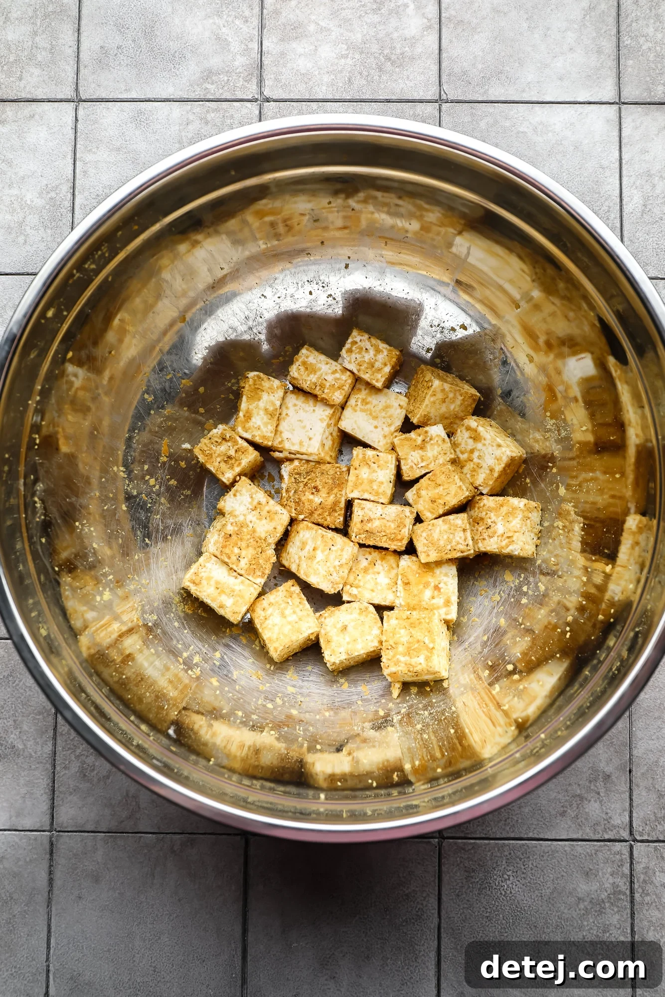 Seasoned tofu cubes in a large metal bowl, ready for frying.