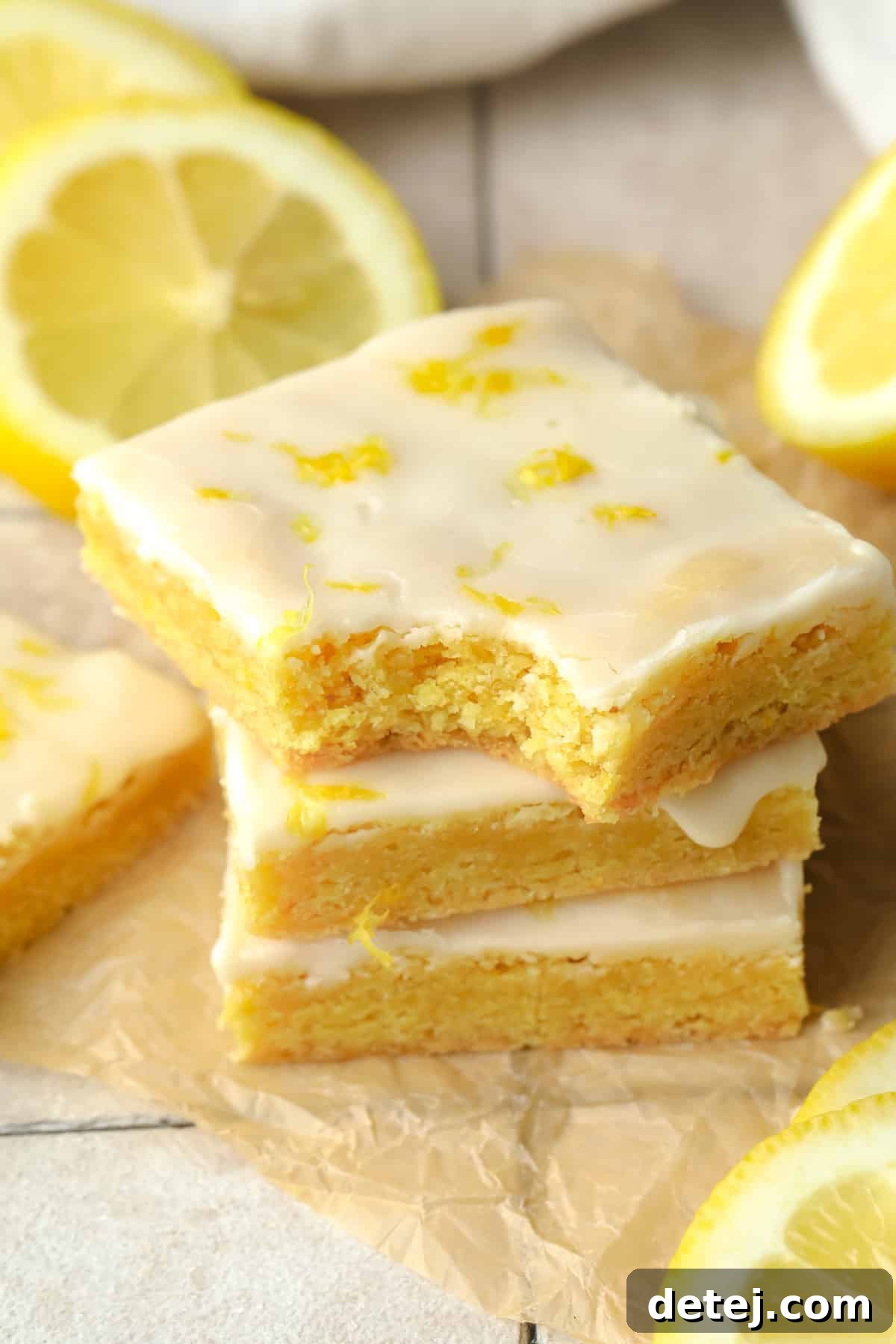 A stack of golden yellow vegan lemon brownies, each topped with a delicate lemon glaze, showcasing their rich, fudgy texture and inviting brightness. Perfect for a refreshing spring dessert.