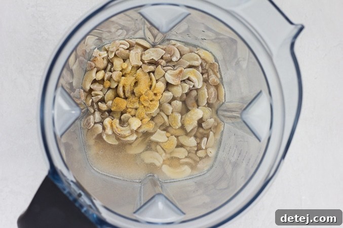 Ingredients for cashew mayo in a blender, including cashews, water, and spices.