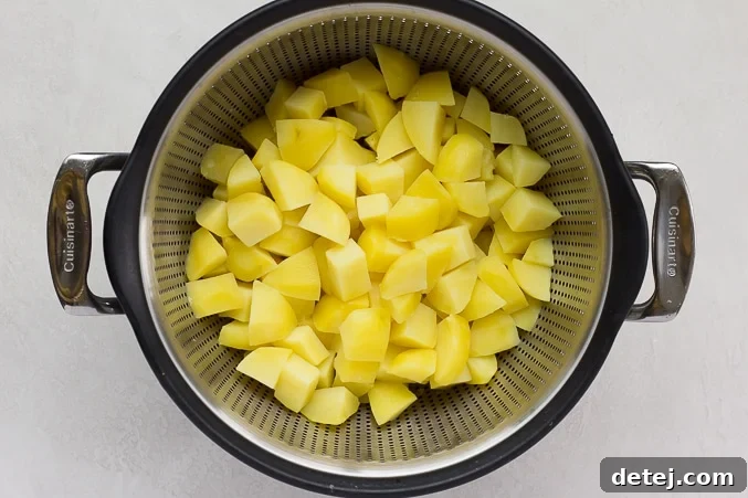 Drained cooked potatoes in a colander, steaming lightly.